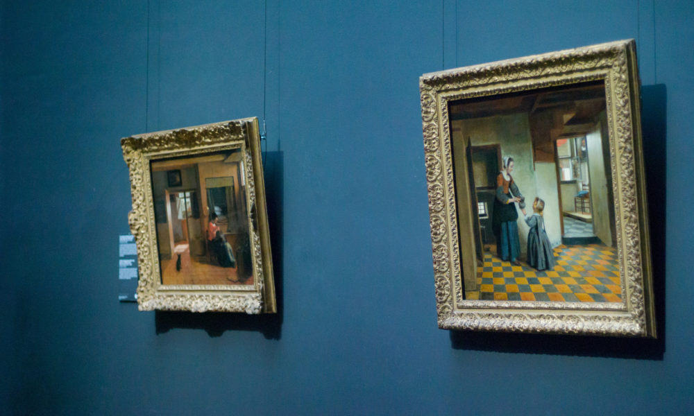 Two framed paintings on a blue wall